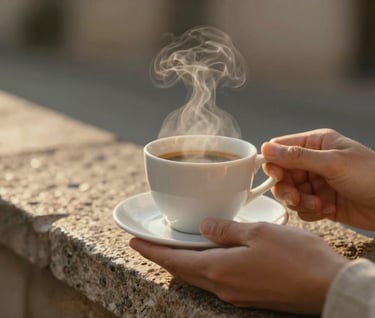 Close-up shot of hands holding a classic white ceramic espresso cup against a rustic stone ledge. Warm golden hour light creates a soft glow, highlighting the steam. The color palette includes rich #6F604F and #C4B29A tones, feeling premium and authentic.