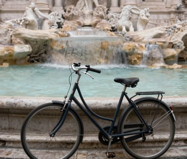 A long exposure shot of a bicycle leaning against a marble fountain in Rome. The water is a soft blur, and the #C4B29A stone looks ancient and textured. The image feels nostalgic and peaceful, like a memory frozen in time.