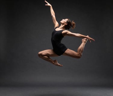 Action sequence video frame, a professional dancer in mid-air movement, spotlight against a dark charcoal background, high contrast, creative and refined.