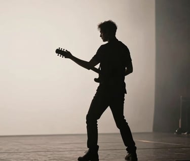 Cinematic wide shot of a musician in silhouette against a soft mist off-white light source, dark stage floor, atmosphere of discipline and focus.
