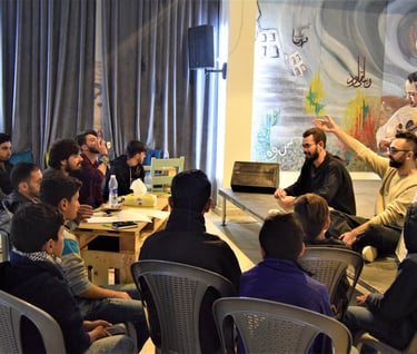 a group of people sitting around a table attending a workshop on rap music composition