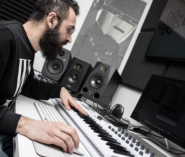 a man in a black shirt is playing a midi keyboard producing music in a studio lebanon