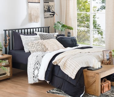 uma cama com uma cama preta e um banco de madeira