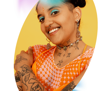 A picture of an indian woman with jewelry smiling at the camera with a yellow background
