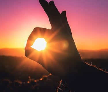 a person holding up a peace sign with the sun setting in the background