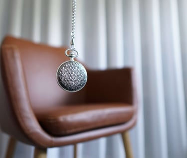 a silver locket with a silver chain in front of a chair