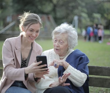 relationships and aging - two women sitting on a bench with a cell phone