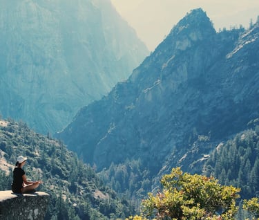 Longevity Travel - a person sitting on a rock with a mountain in the background