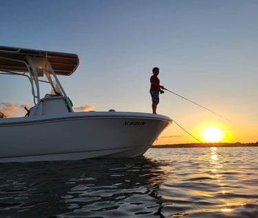 a man fishing on a boat at sunset