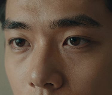 A close-up artistic portrait focusing on the subject's eyes, with a warm muted earthy tan light source from the side. Soft grain, cinematic film style.