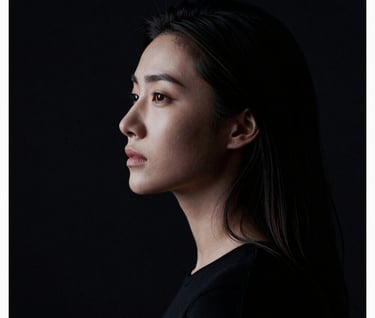 A high-contrast cinematic portrait of a woman, styled like a minimalist film poster. The composition uses negative space with midnight black tones and sharp soft white highlights on the profile.