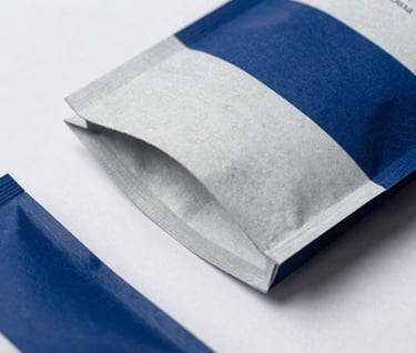 Detail of high-quality branded packaging materials on a soft white background, featuring steel blue accents and subtle paper textures, professional lighting, International / Western design style.