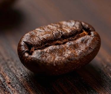Extreme close-up of a single roasted coffee bean resting on a polished dark wood surface. Dramatic lighting showing every crack and texture. Dark brown and tan palette.