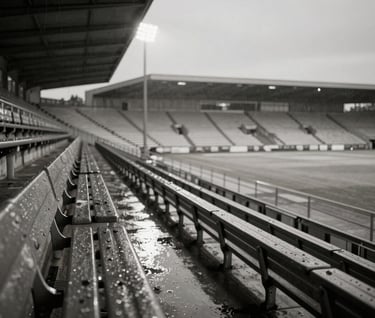 An empty, rain-slicked stadium bench in Amsterdam at dusk, illuminated by a single distant spotlight, creating long shadows and a sense of quiet tension, charcoal and off-white color palette.