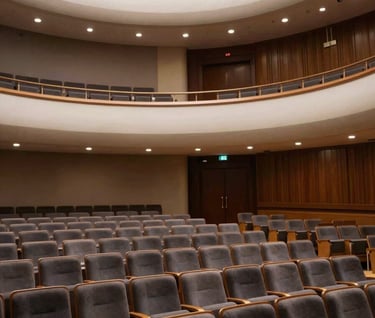 A landscape photography shot of a modern, empty auditorium in the US with plush seating and architectural lighting in off-white and charcoal tones, reflecting a sophisticated performance venue.