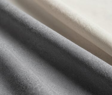 Detailed close-up photography of high-quality fabric texture and materials, highlighting professional craftsmanship, muted medium grey and soft off-white colors, elegant composition.