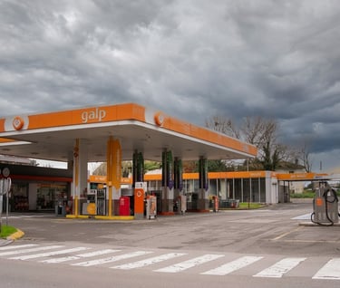 Una gasolinera Galp con marca naranja y surtidores de combustible bajo un cielo nublado.