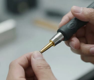 Detailed shot of a specialized gold-tipped PDR rod #E7C670 being used by a technician's hand. Focus is on the precision and the contact between tool and metal. Leading professional style.