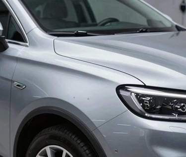 The 'After' shot: The same car panel from the previous image, now perfectly smooth with no trace of the dent. The metallic paint sparkles under studio lights, reflecting a clean workshop. Professional and high-quality finish.