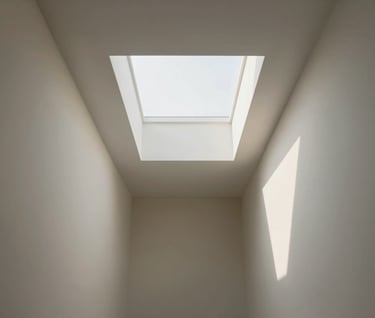 A hallway featuring clever skylights that create dramatic, warm shadows on #F9F6EE colored walls.