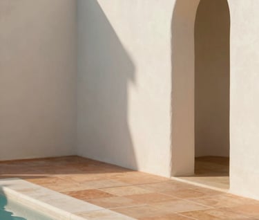 A close-up architectural detail shot of natural materials. Smooth off-white lime wash walls (#F9F6EE) meet warm terracotta floor tiles (#B85C3D) in a pool of soft afternoon sunlight.