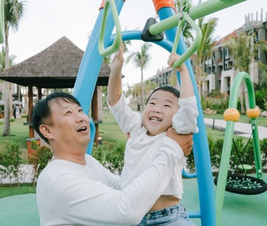 Family photography session at The Apurva Kempinski Bali playground area featuring joyful parent and child interaction.
