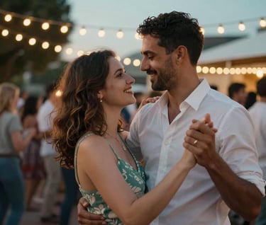 A candid photography shot of a couple dancing at an outdoor evening party in a South African city setting. Warm string lights reflect Sage Teal and Pearl White tones, evoking a sense of joy.