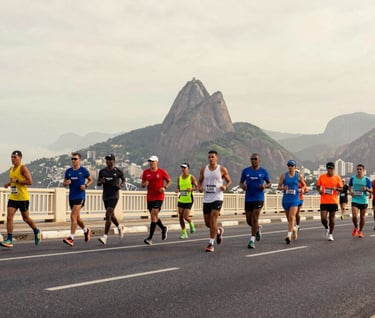 A wide-angle shot of a group of marathon runners crossing a bridge in Rio de Janeiro. The composition shows the scale of the event. The sky is a soft #F2F1ED and the asphalt a dark #403B3B. Vibrant yet elegant mood.