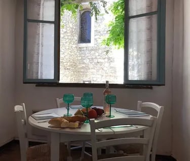 Salle à manger d’une maison de vacances à Quillan avec fenêtres ouvertes et vue sur l’église