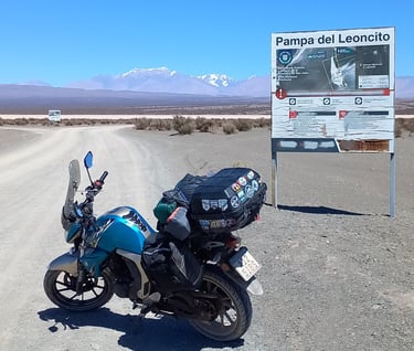 a motorcycle parked on a dirt road near a sign