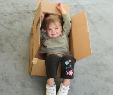 a little girl sitting in a cardboard box