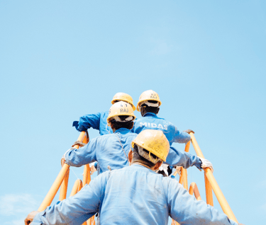 two men in blue workwears and helmets on a ladder ladder