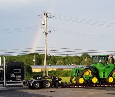 a tractor trailer with a rainbow - colored rainbow in the background