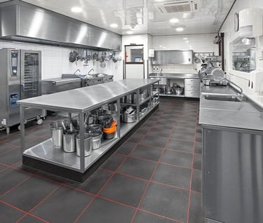 Full view of a bustling commercial kitchen with durable stainless steel benchtops. About us.