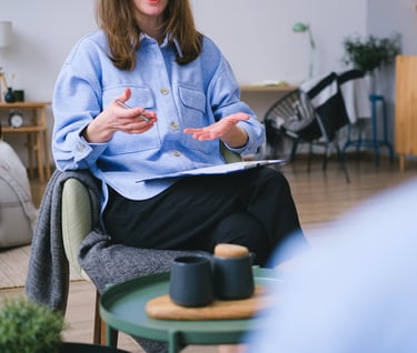a woman in a blue shirt and black pants sitting in a chair