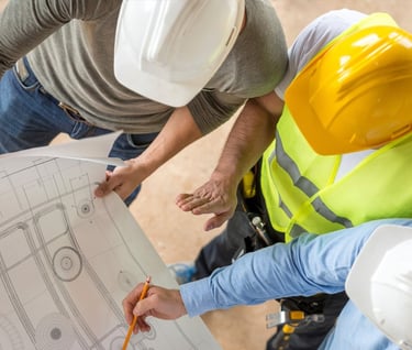 two men in safety vests and helmets standing in front of a building