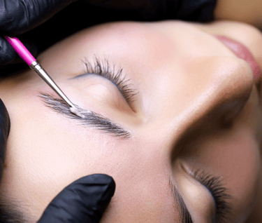 a woman getting her eyebrows laminated by a professional brow artist