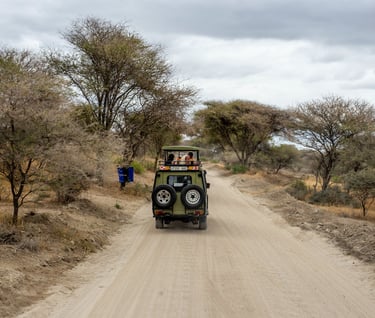 a jeep driving down a dirt road with people in the background