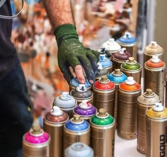 a person holding a paint can and a spray can