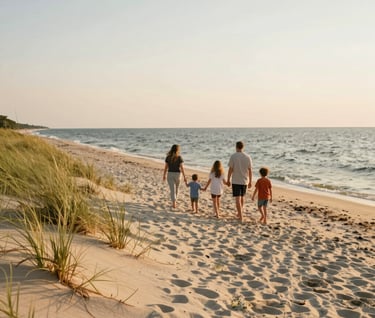 A wide photography shot of a family walking along the dunes of a Lake Michigan beach in West Michigan. The scene is illuminated by the warm, soft light of the golden hour. The composition is expansive, showing the light cream sand and the gentle water, conveying a sense of freedom and timeless love.
