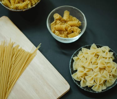 An assortment of pasta (spaghetti, fussili, and farfalle) on a table