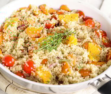 Quinoa salad with tomatoes, orange segments, carrots, and rosemary.