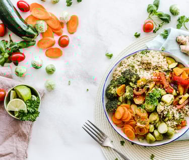 A colorful vegetable salad bowl with carrots, broccoli, cucumber, zuchinni, quionoa, and cherry tomatoes
