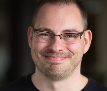 Richard Stevens smiling, wearing  glasses and a black shirt
