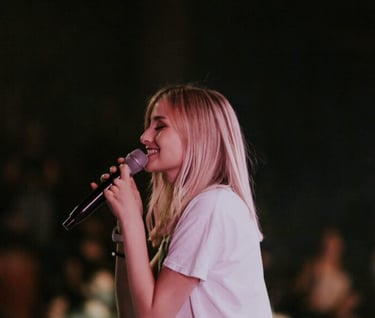 a woman singing into a microphone while holding a microphone
