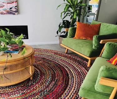 a living room with a green couch and a table with a potted plant and jute fabric carpet