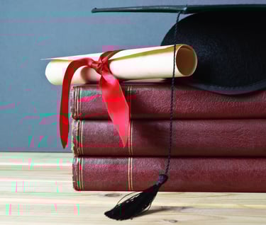 Stack of red books with a diploma, tied with a red ribbon, and a graduation cap on top