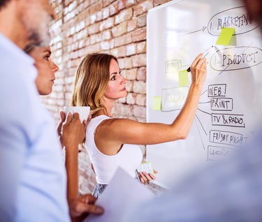 Consultants planning B2B marketing strategy and optimizing client acquisition workflow on whiteboard