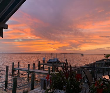 a sunset view of a dock with chairs and tables