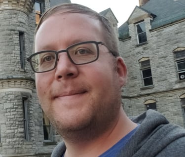 a man in glasses and a blue shirt is taking a selfie